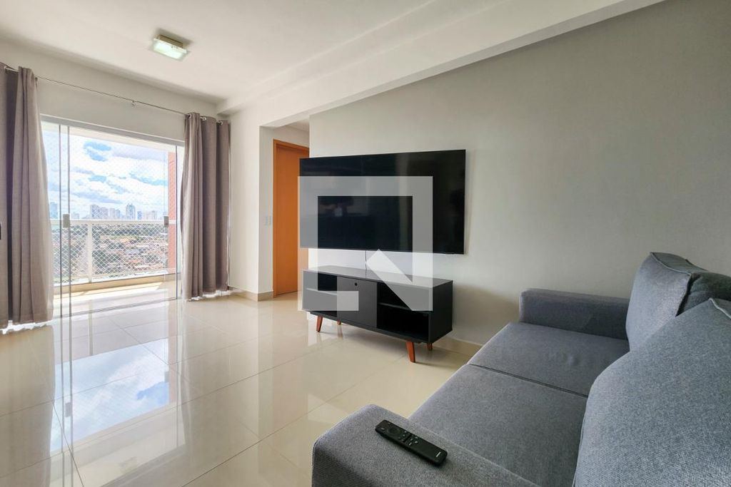 Sala integrada com sofá, TV e porta para a varanda